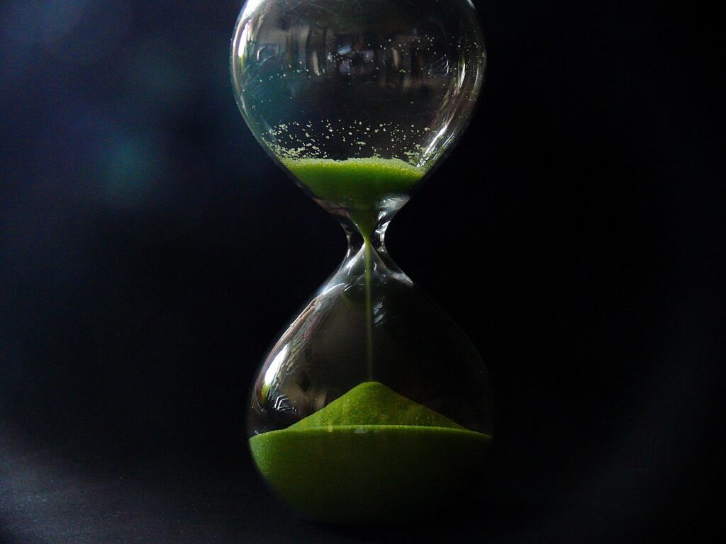 An hourglass, partially lit, with more sand in the bottom than in the top