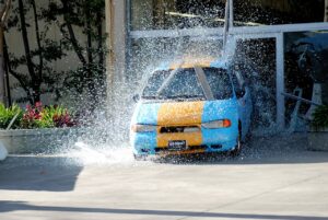 A blue and yellow car crashing through glass doors