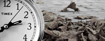 A clock superimposed on a picture of fallen leaves on a path - time is moving on