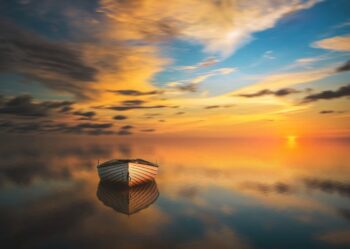 A boat floating on calm waters as the sun sets, a scene of serenity, reflecting the serenity you feel when you release negative emotions with Time Line Therapy®