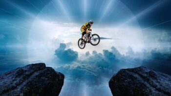 A mountain biker jumping between two peaks, reaching the dream