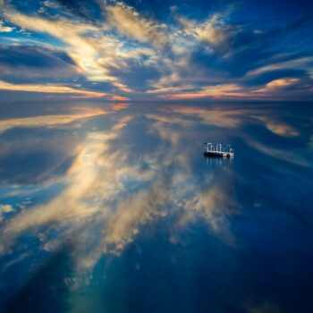 A completely still lake reflecting the light and clouds in the sky. A picture of serenity, serenity which you can achieve by overcoming anxiety.