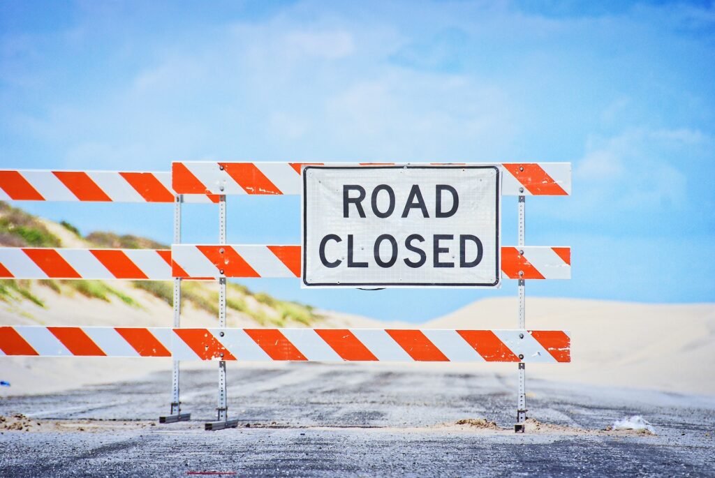 A barrier, blocking the road, with a sign saying road closed. What's getting in your way?