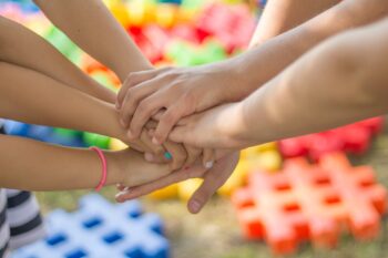 Children's hands, unified in a circle, showing that working together is the way forward.