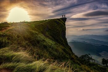 Two people atop a cliff, celebrating their success