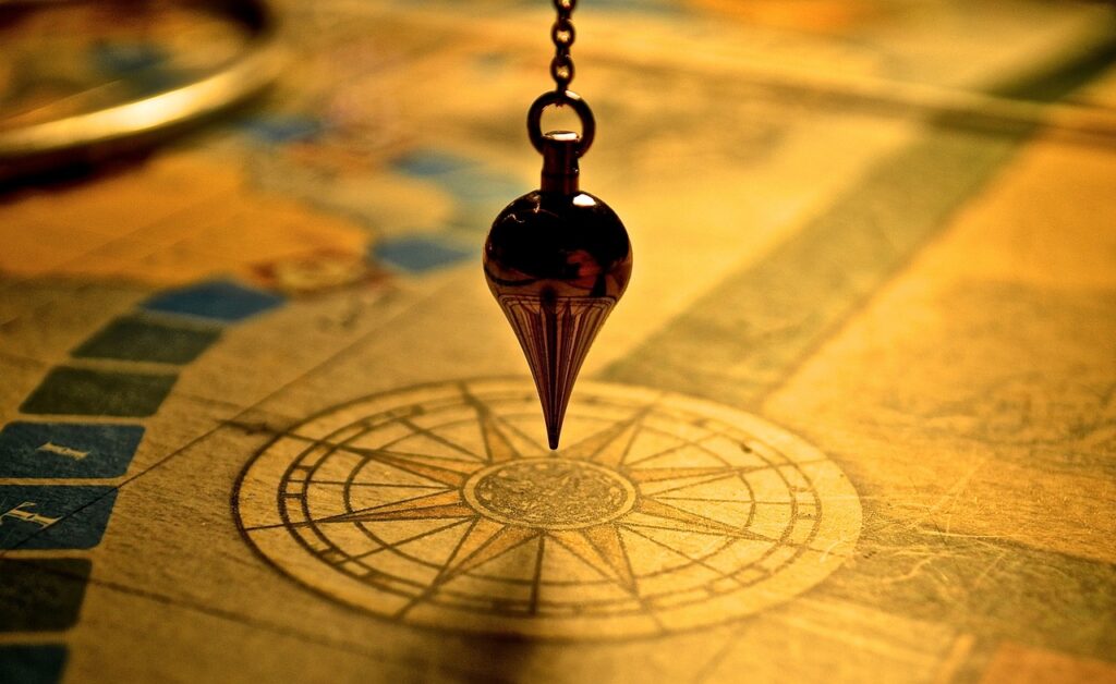 A pendulum suspended above a compass on a map. Which direction are you going in?