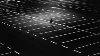 A lone person, walking across an empty car park