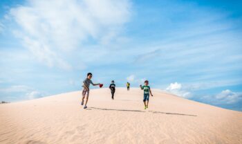 Children running down a sand dune, not a care in the world