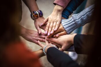 A group of people, hands meeting in the middle, working together in rapport